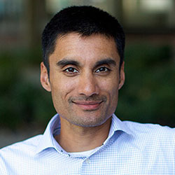 Dr. Jay Sarthy, smiling, and wearing a light blue open-collared shirt 