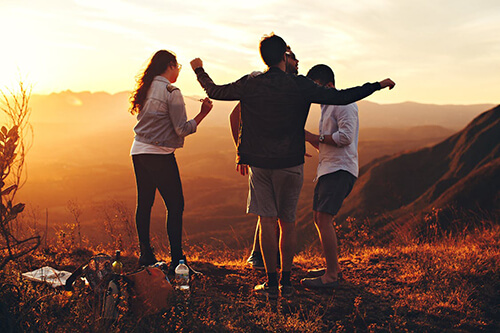 three people standing on a hill in the evening