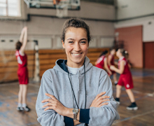 Coach smiles with basketball players in background