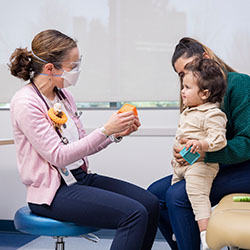 A Seattle Children's provider holds a toy block up to a young patient