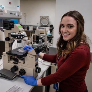 Young woman in a lab operating a microscope